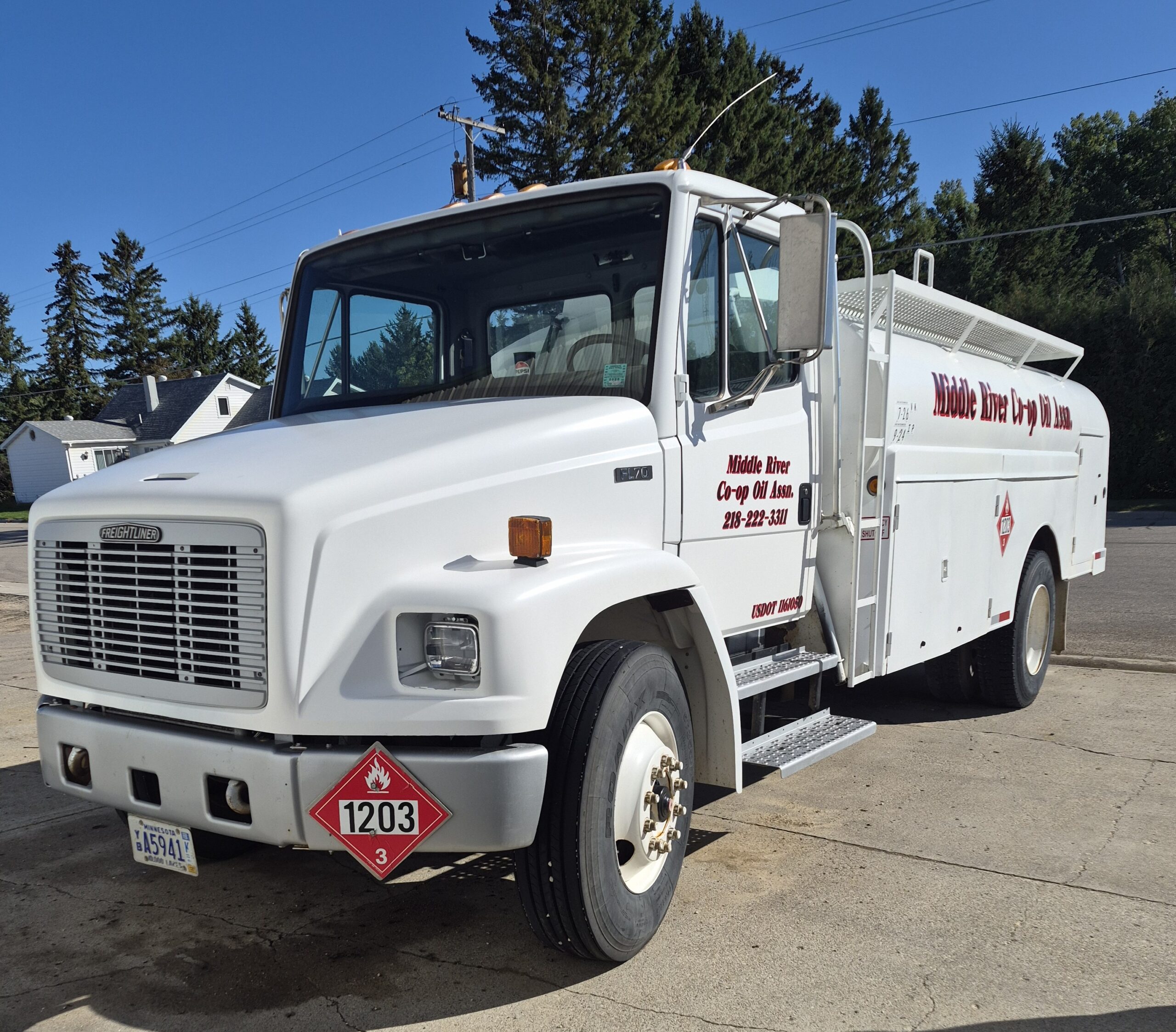 White Freightliner fuel truck from Middle River Co-op Oil Assn. parked under a clear blue sky with pine trees behind